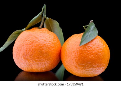 Two mandarin with leaf isolated on a black background