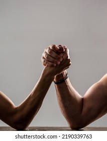 Two Man's Hands Clasped Arm Wrestling, Strong And Weak, Unequal Match. Heavily Muscled Man Arm Wrestling A Puny Weak Man.