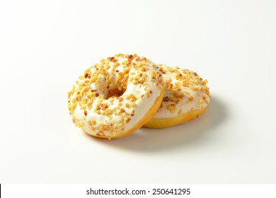 Two maple-glazed ring donuts topped with chopped nuts