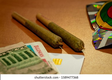 Two Marijuana Joints Are Displayed With An Illinois ID Card And Money On A Table. Recreational Cannabis Legalization In Illinois. 