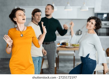 Two married couples perform pair dance during holiday, have fun, move and jump in dining room. family event is held with fun music and dancing