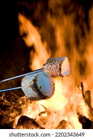 Two Marshmallows Being Roasted To Make Smores Over A Campfire