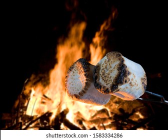 Two Marshmallows Being Roasted Over A Campfire To Make Smores 