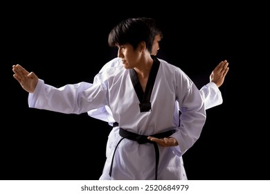 Two martial artists wearing white taekwondo uniform demonstrates defensive stance against dark background - Powered by Shutterstock