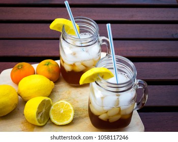 Two mason jars with cold drinks and fruits in wooden table 