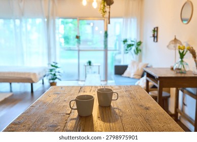 Two matching ceramic mugs side by side on rustic wooden table with soft natural light and blurred background