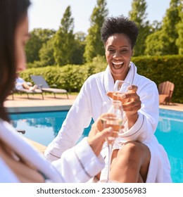 Two Mature Female Friends Wearing Robes Outdoors On Loungers Drinking Champagne On Spa Day - Powered by Shutterstock