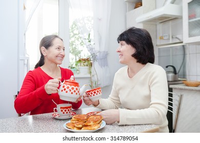 Two Mature Girlfriends Talking Over Coffee In  Kitchen.