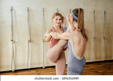 Two Mature Women Doing Yoga Pose Together Standing And Putting Leg On Shoulder