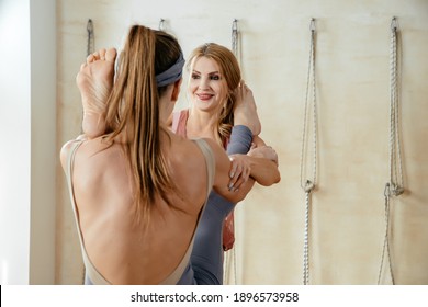 Two Mature Women Doing Yoga Pose Together Standing And Putting Leg On Shoulder