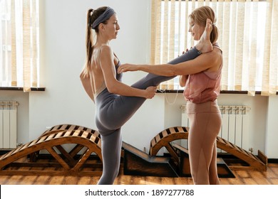 Two Mature Women Doing Yoga Pose Together Standing And Putting Leg On Shoulder