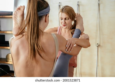 Two Mature Women Doing Yoga Pose Together Standing And Putting Leg On Shoulder