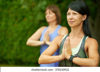 Two Mature Women Keeping Fit By Doing Yoga In The Summer