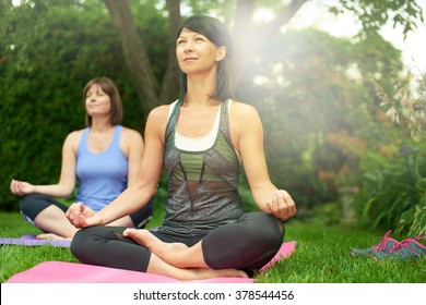 Two Mature Women Keeping Fit By Doing Yoga In The Summer