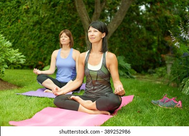 Zwei erwachsene Frauen, die im Sommer Yoga machen