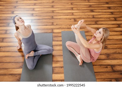 Two Mature Women Stretching Together In Yoga Studio Before Yoga Class