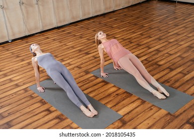 Two Mature Women Stretching Together In Yoga Studio