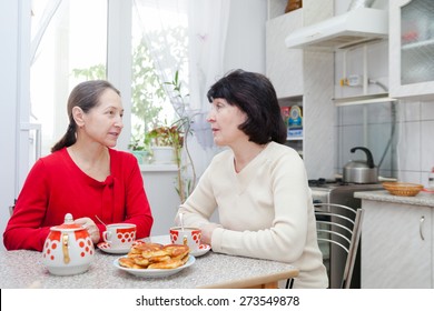 Two Mature Women Talking At   Kitchen Table With   Cup Of Tea.  