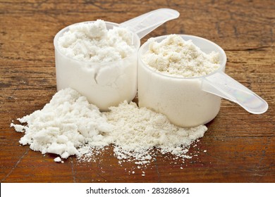 Two Measuring Scoops Of Whey Protein Powder - Isolate (white) And Concentrate (creamy)