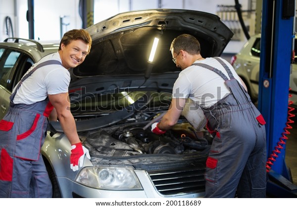 Two mechanics fixing\
car in a workshop
