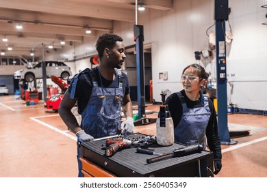 Two mechanics, a man and a woman, working together in a professional garage, discussing car repair strategies - Powered by Shutterstock