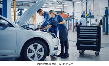 Two Mechanics in a Service are Inspecting a Car After They Got the Diagnostics Results. Female Specialist is Comparing the Data on a Tablet Computer. Repairman is Using a Ratchet to Repair the Faults. - Powered by Shutterstock