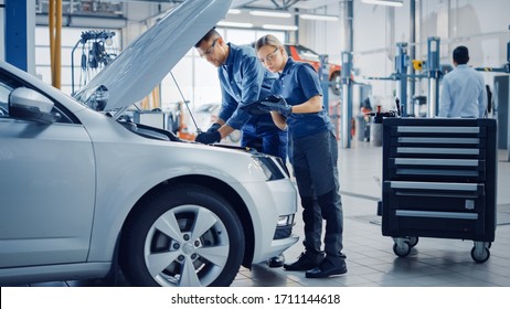 Two Mechanics in a Service are Inspecting a Car After They Got the Diagnostics Results. Female Specialist is Comparing the Data on a Tablet Computer. Repairman is Using a Ratchet to Repair the Faults. - Powered by Shutterstock