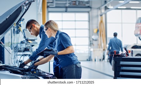 Two Mechanics in a Service are Inspecting a Car After They Got the Diagnostics Results. Female Specialist is Comparing the Data on a Tablet Computer. Repairman is Using a Ratchet to Repair the Faults. - Powered by Shutterstock