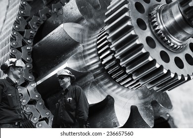 Two Mechanics, Workers With Large Gears And Cogs Machinery