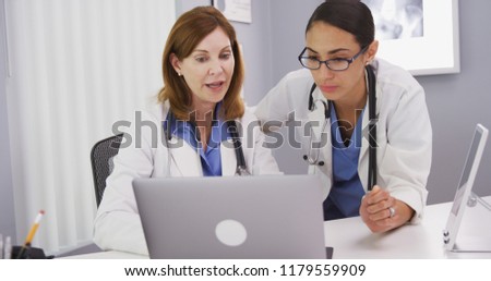 Two medical doctors using notebook computer to discuss patients healh condition