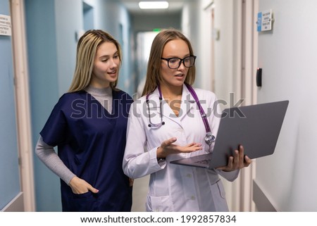 Two medical doctors using notebook computer to discuss patients healh condition