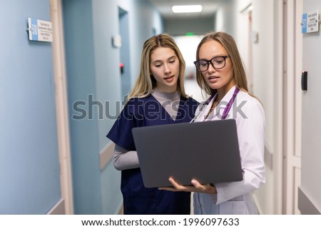 Two medical doctors using notebook computer to discuss patients healh condition