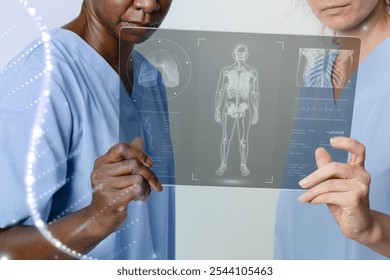 Two medical professionals examine a digital X-ray. They focus on the skeletal structure displayed on the transparent screen, highlighting advanced medical technology. Medical team reviewing x-ray. - Powered by Shutterstock