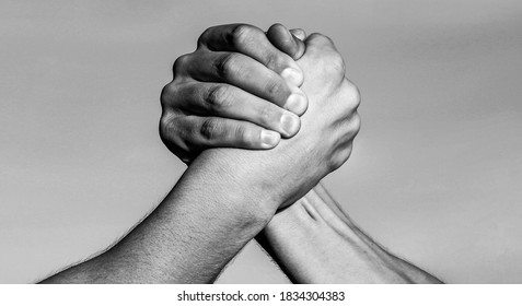 Two men arm wrestling. Arms wrestling. Hand, rivalry, vs, challenge, strength comparison. Two muscular hands.Friendly handshake, friends greeting, teamwork Black and white