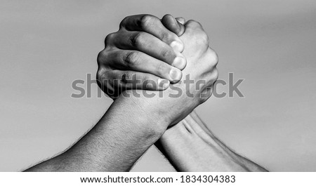 Two men arm wrestling. Arms wrestling. Hand, rivalry, vs, challenge, strength comparison. Two muscular hands.Friendly handshake, friends greeting, teamwork Black and white