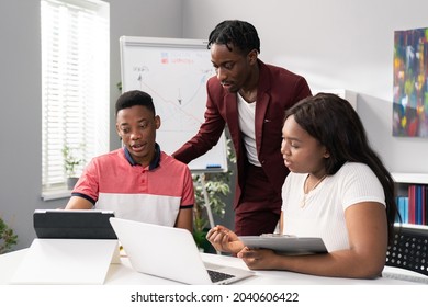 Two Men And Beautiful Woman Sit In An Office In The Morning, Preparing For Work, A Conference, A Training Session, Discussing Strategy, Talking About A Project, Browsing The Internet For Information