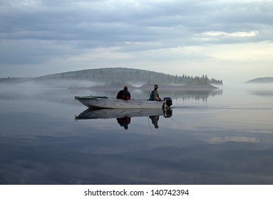  Two Men In A Boat Fishing On A Calm Lake