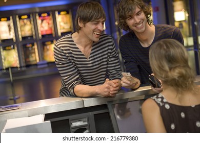 Two Men Buying A Movie Ticket At The Box Office.