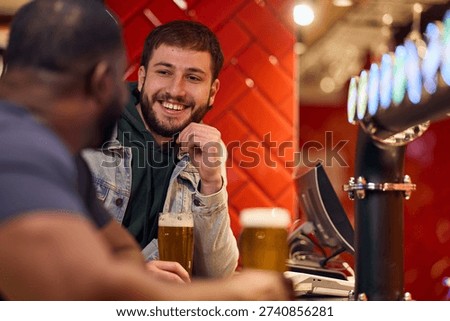 Two men chat at a bar, sharing beers and smiles. A casual, modern pub setting with warm lighting conveys friendship, relaxed vibes, and social connection.
