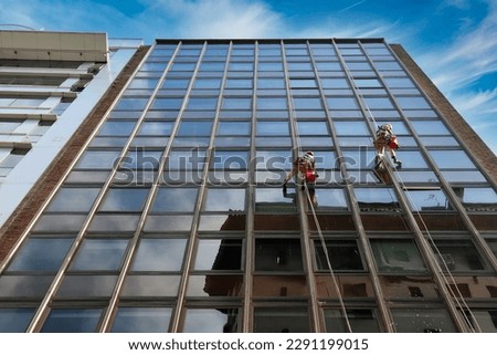 two men cleaning the windows on the heights of a skyscraper