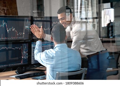 Two men colleagues traders sitting at desk at office monitoring stock market getting profit achieving success giving high five doing great job laughing happy trading concept - Shutterstock ID 1809388606