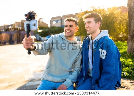 Two men creating content for their vlog channel, recording a video with a smartphone and external microphone
