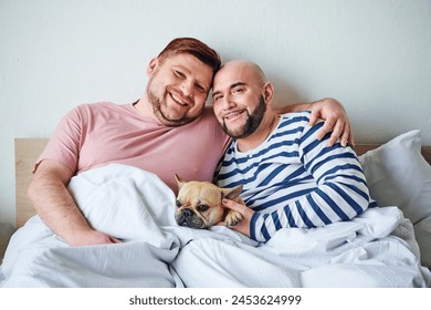 Two men cuddle in bed with their French bulldog. - Powered by Shutterstock