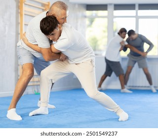 Two men of different ages in judo sparring - older man throws young guy to the mat - Powered by Shutterstock