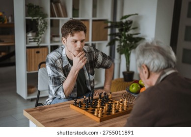 Two men of different generations playing a strategic game of chess at home, focusing on the board, representing concentration, leisure, and inter generational interaction