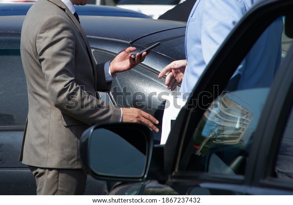 Two men discussing a car\
accident while standing next to the cars. Calling the inspector.\
Simplified road accident registration protocol. Without a\
face