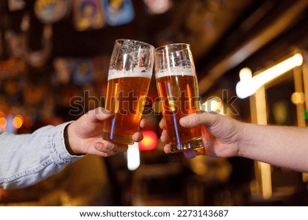 Two men drinking beer at the bar. They celebrate St. Patrick's Day. They are having fun