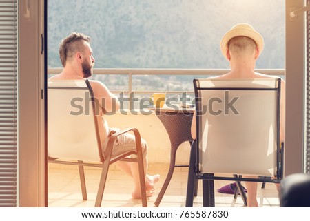Two men drinking coffee on the balcony