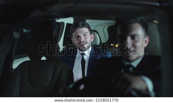 Two men drive in car and\
talk.