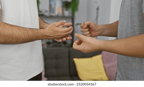 Two men engaging in a friendly rock-paper-scissors game indoors, with a focus on hands and gestures.